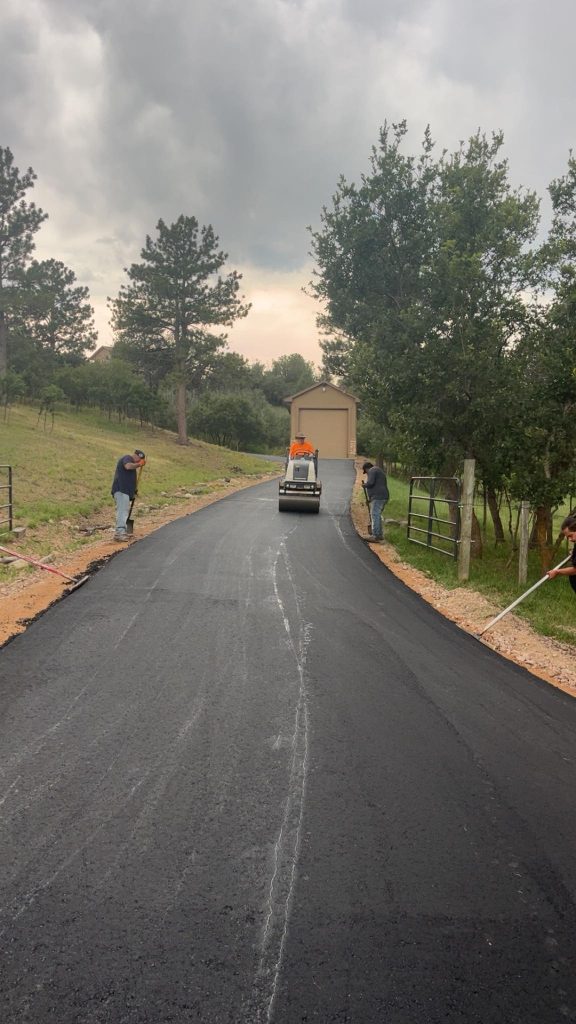 crew compacting asphalt on a driveway