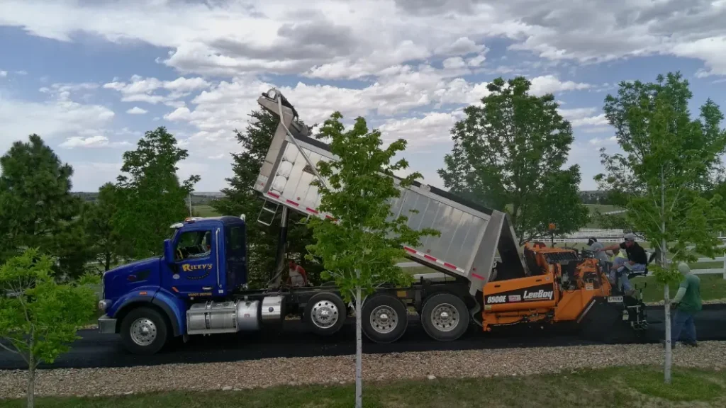 Truck and paver working together to lay driveway