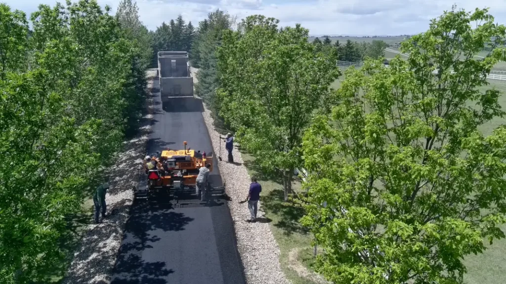 Overhead view of paver laying asphalt while truck is driving away